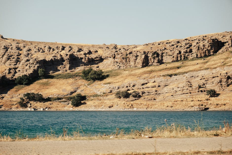 A serene rocky landscape with a blue lake under a clear sky, perfect for nature enthusiasts.