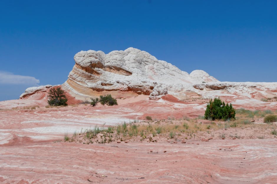 Scenic view of dramatic white and red rock formation in desert under clear blue sky.